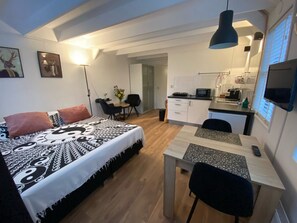 A compact studio apartment with a bed, a dining table, a kitchenette, and a small seating area. - Holiday Apartment With 1 Bedroom (Schoorl)