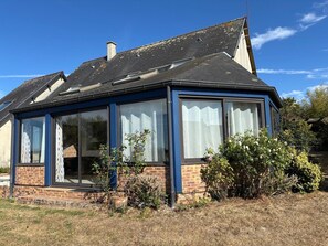 A house with a sloped roof, large windows, and a brick exterior. - Normandy Gite With Bay Views (Courtils)
