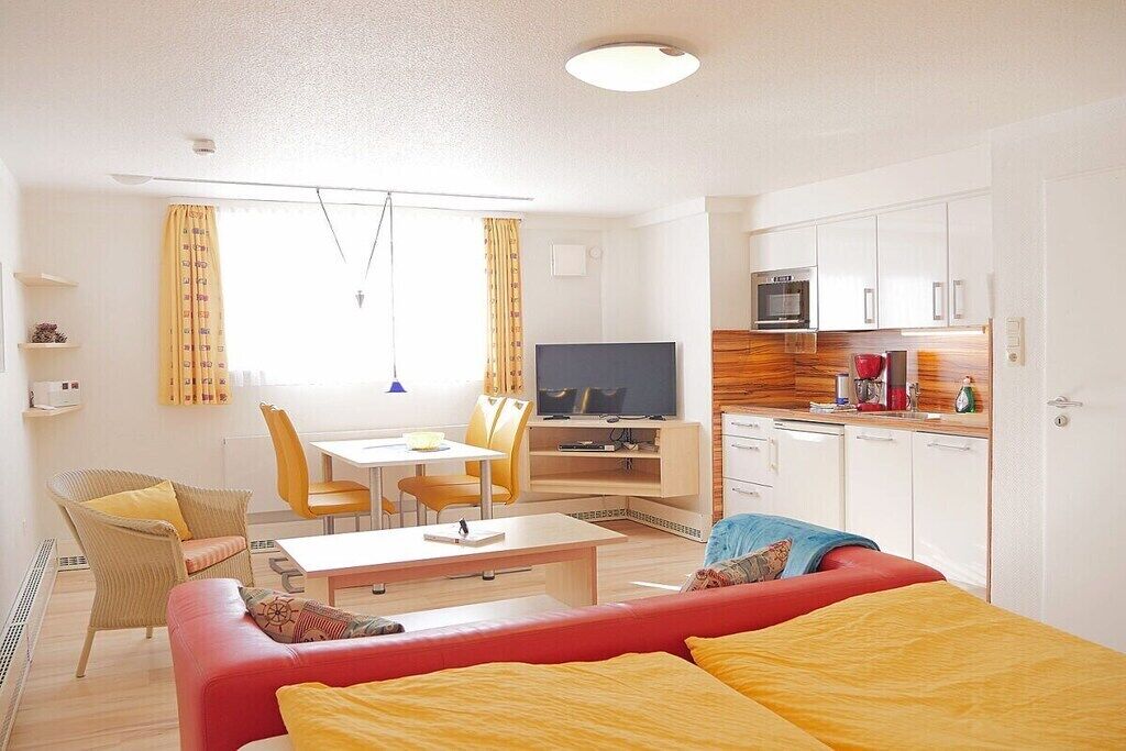 A compact living space with a kitchenette, a dining area, and a seating area with a television.