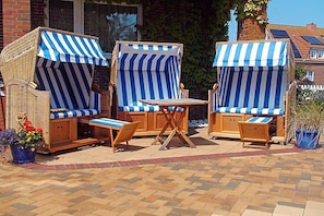An outdoor seating area with striped awnings and wooden furniture. - Seestern 7 Apartment House Seestern (Norderney)