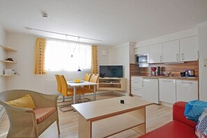 A modern living room with a dining area, a kitchen, and a television. - Seestern 7 Apartment House Seestern (Norderney)
