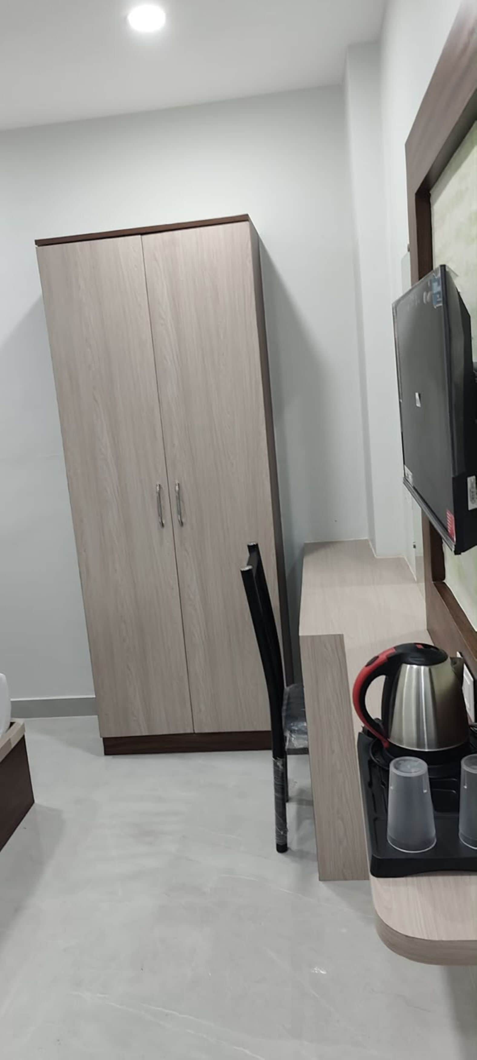 Una habitación con armario, televisión y cafetera sobre una encimera.