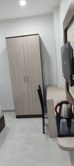 Una habitación con armario, televisión y cafetera sobre una encimera.