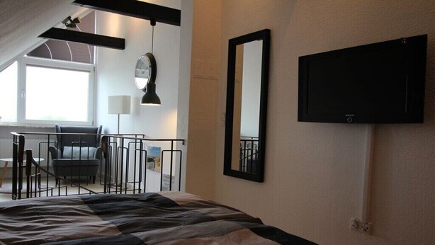 Une chambre d’hôtel avec un lit, un bureau, une chaise, une télévision et une fenêtre.