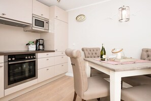 Eine kompakte Küche mit Mikrowelle, Backofen und einer Essecke mit Tisch und Stühlen.