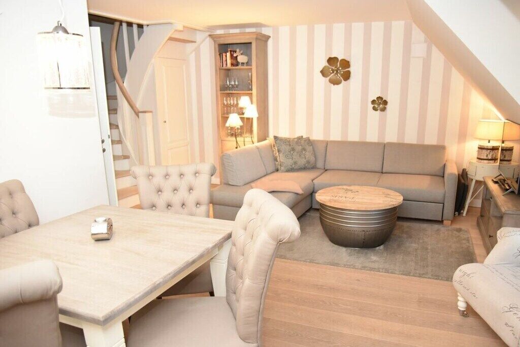 Een gezellige woonkamer met een bank, een rond salontafeltje en een eethoek met een tafel en stoelen.