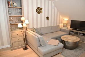 A modern living room with a sofa, a coffee table, a TV, and a bookshelf. - Villa Jansen 5 - OG/DG (Wenningstedt)
