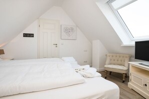 A bedroom with a bed, a chair, a television, and a skylight. - Villa Jansen 5 - OG/DG (Wenningstedt)