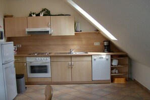 A compact kitchen with a gas stove, oven, dishwasher, and a small countertop area. - Holiday apartment with 1 bedroom (Cuxhaven)