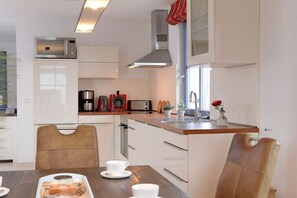 A modern kitchen with white cabinetry, stainless steel appliances, and a wooden countertop. - Thatched house "Huus Poeler Wiek" (Zierow)