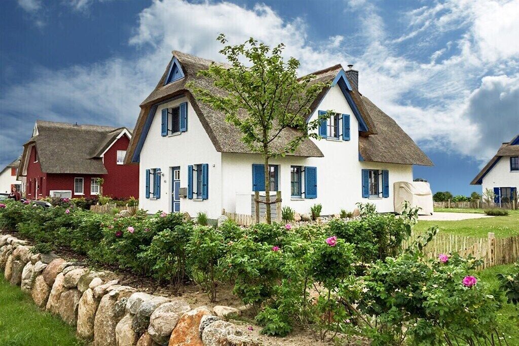 A traditional house with a thatched roof, white walls, and blue shutters.