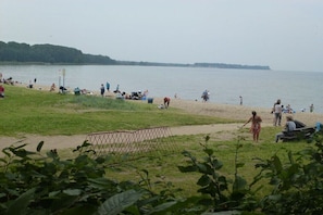 A beach with people, a grassy area, and a body of water. - Thatched house "Huus Poeler Wiek" (Zierow)
