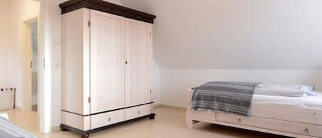 A bedroom with a bed, a wardrobe, and a rug.