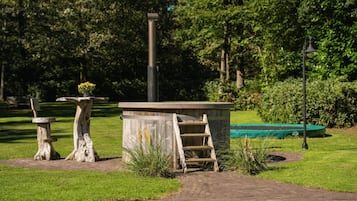 A park with a wooden structure, a bench, and a green boat in the background.