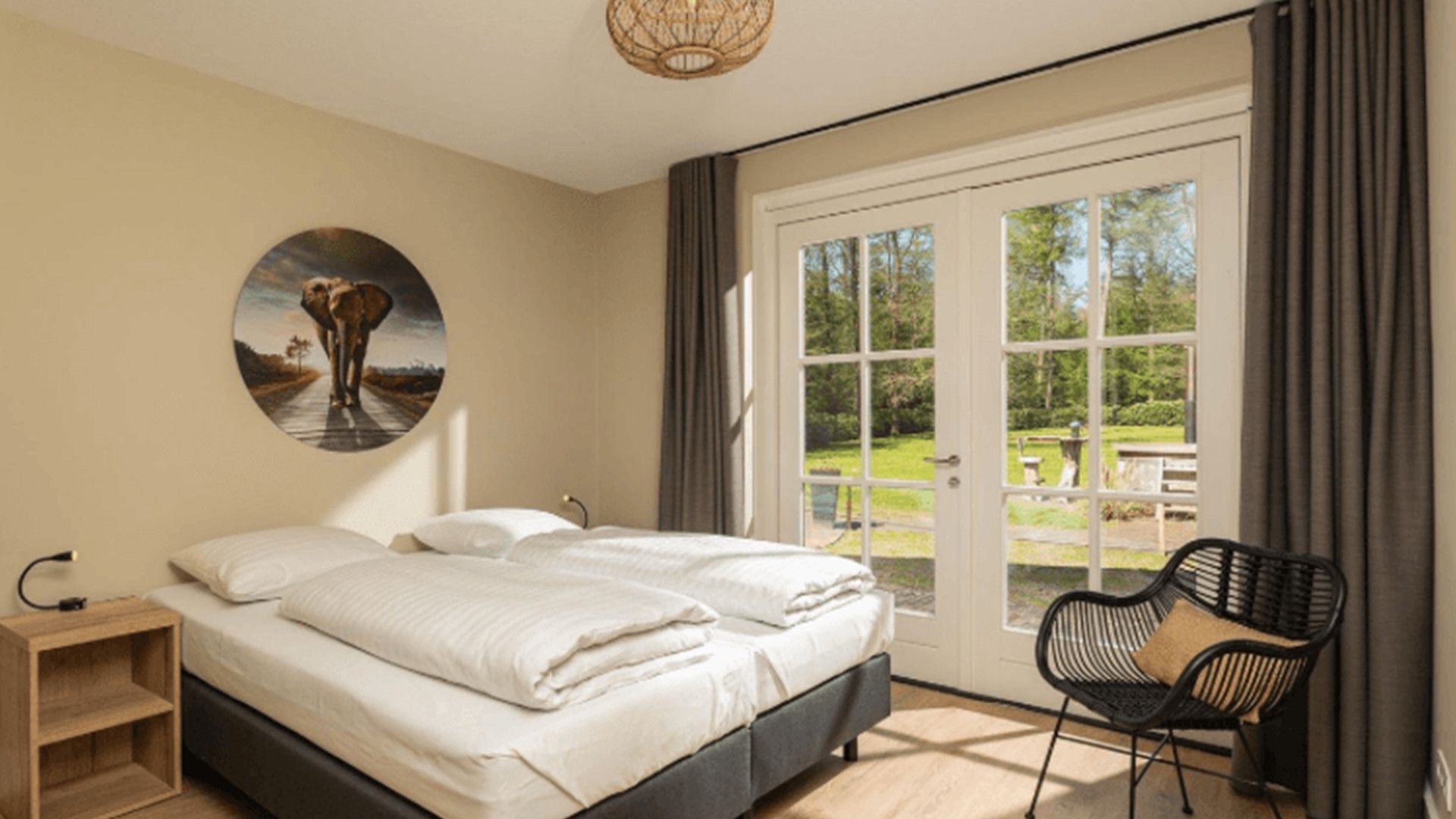 Une chambre à coucher avec un lit, une chaise, une table de chevet et une grande fenêtre.