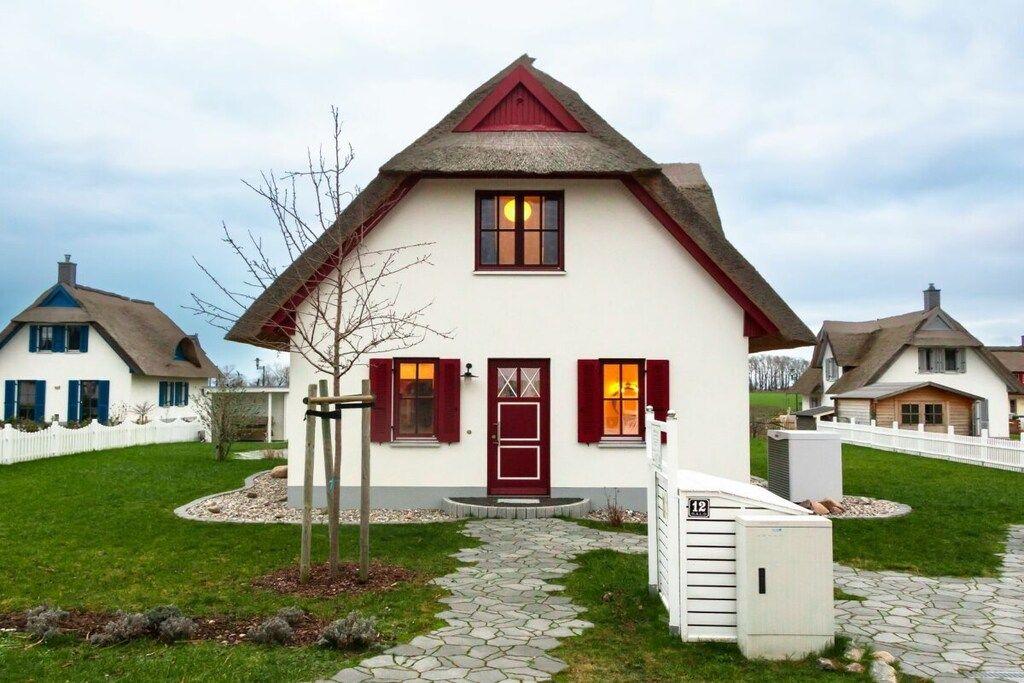 A single-story house with a steeply pitched roof, a front door with a glass panel, and a small porch area.