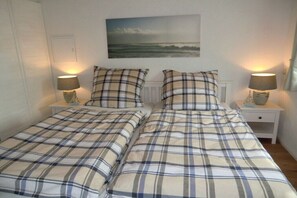 A double bed with a plaid bedspread, two bedside tables with lamps, and a painting on the wall. - Fischerkate Norderfeld (Dollerup)