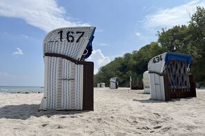 Ein Strand mit nummerierten Liegen und Sonnenschirmen, der einen Verleihbereich kennzeichnet.