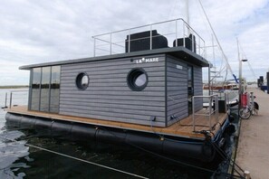 A floating structure named 'LA MARE' with a deck and a small enclosed area, docked at a marina. - Houseboat in Wendtort with swimming pool (Wendtorf)