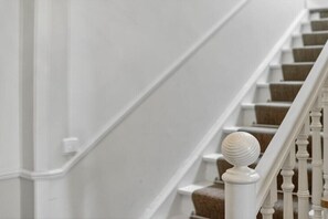Un escalier avec des balustres blanches et une main courante en bois.