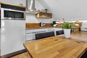 Une cuisine moderne équipée d’un four encastré, d’une machine à café et d’un vase rempli de fleurs posé sur le plan de travail.