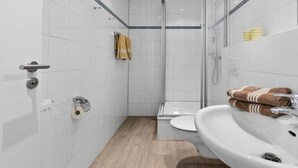 Ein modernes Badezimmer mit Toilette, Waschbecken und Dusche.