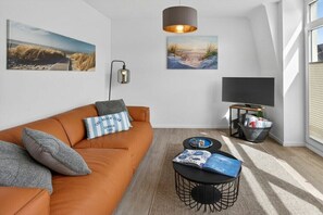 Un salon moderne avec un canapé, une table basse et un téléviseur.