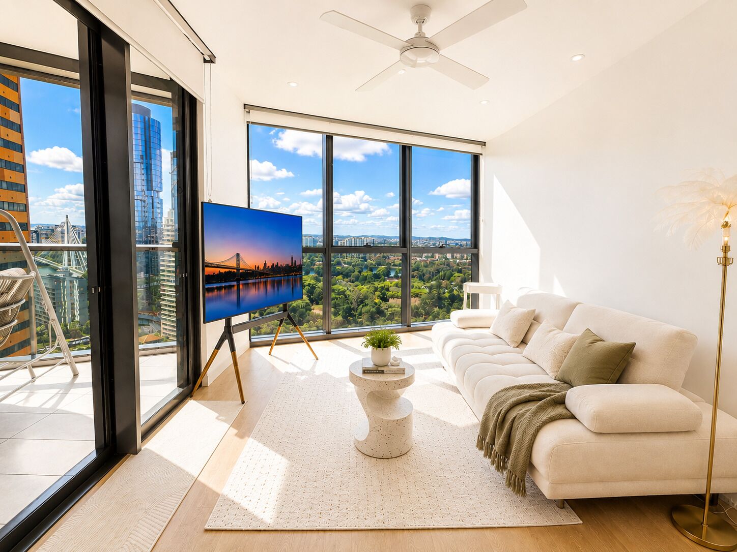 A modern living room with a large window, a white sofa, a coffee table, and a television displaying a cityscape.