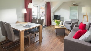 Ein modernes Wohnzimmer mit Essbereich, einer Sofagarnitur und einem Fernseher.