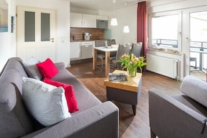 Een moderne woonkamer met een bank, salontafel en een eethoek met stoelen.