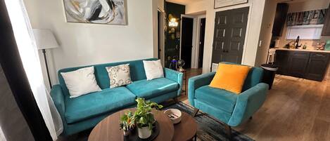 A living room with a sofa, two armchairs, a coffee table, and a ceiling fan.