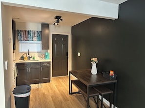 A compact kitchen with dark cabinets, a window with blinds, a coffee maker, and a trash bin. - Summerhill ATL Gem Walk to Stadium, Bars & Dining (Atlanta)