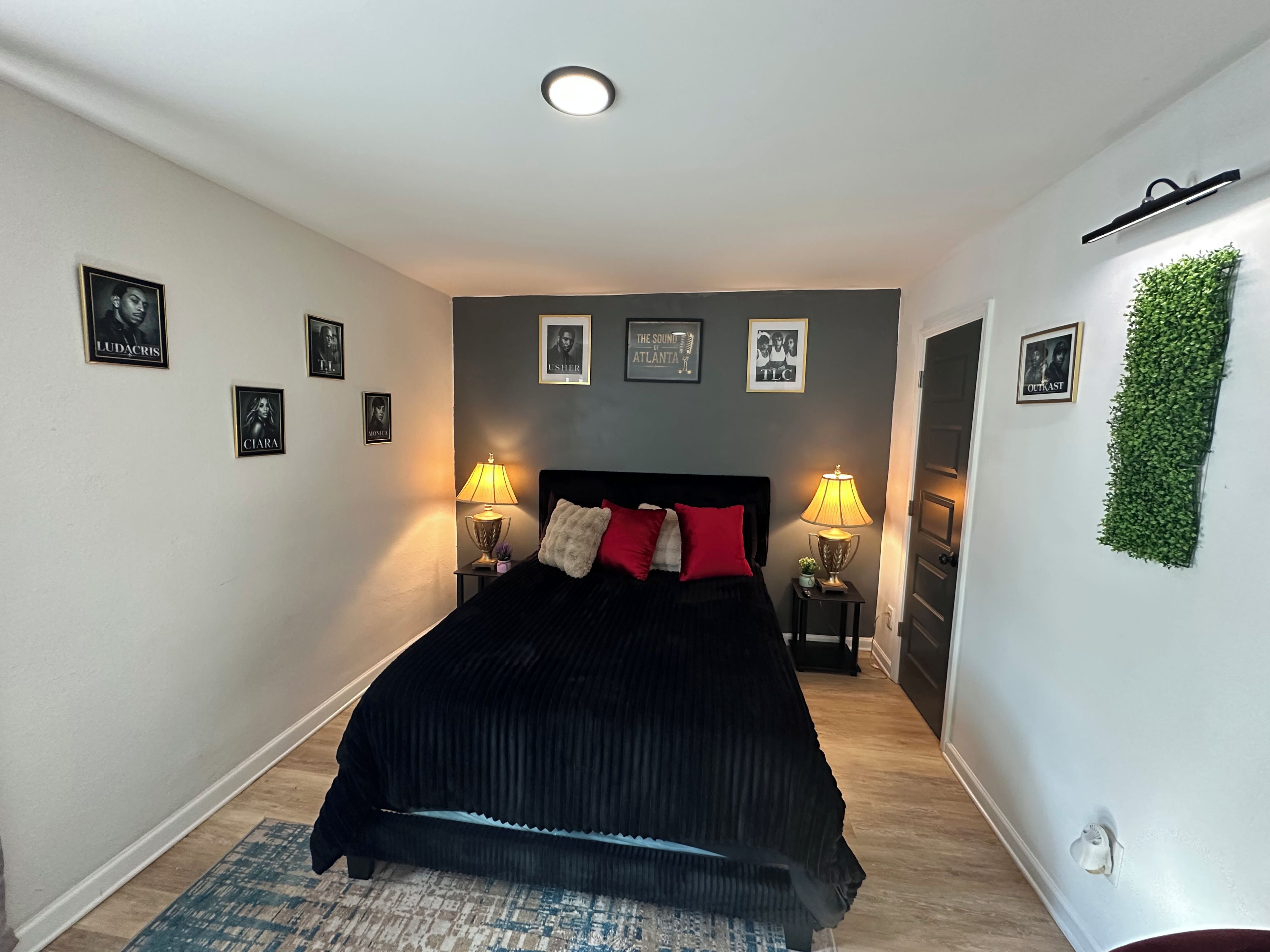 A bedroom with a bed, two bedside lamps, a wall-mounted light, and framed pictures.