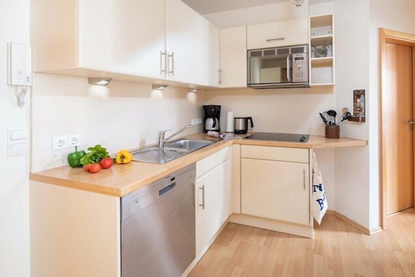 Een kleine keuken met een vaatwasser, een magnetron en een spoelbak.