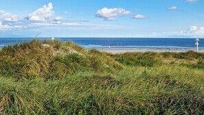 Ein Strand mit Dünen, blauem Himmel und ruhiger See.