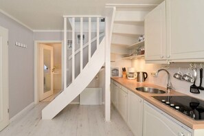 Eine Küche mit weißer Treppe, einem Spülbecken, Schränken und einer Arbeitsplatte.