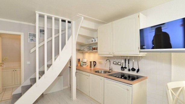 A kitchen with white cabinets, a wooden countertop, a built-in stove, and a hanging pot rack. - Apartment in Rantum with swimming pool (Rantum)