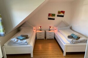 Une chambre avec deux lits simples, des tables de chevet et des œuvres d’art murales.