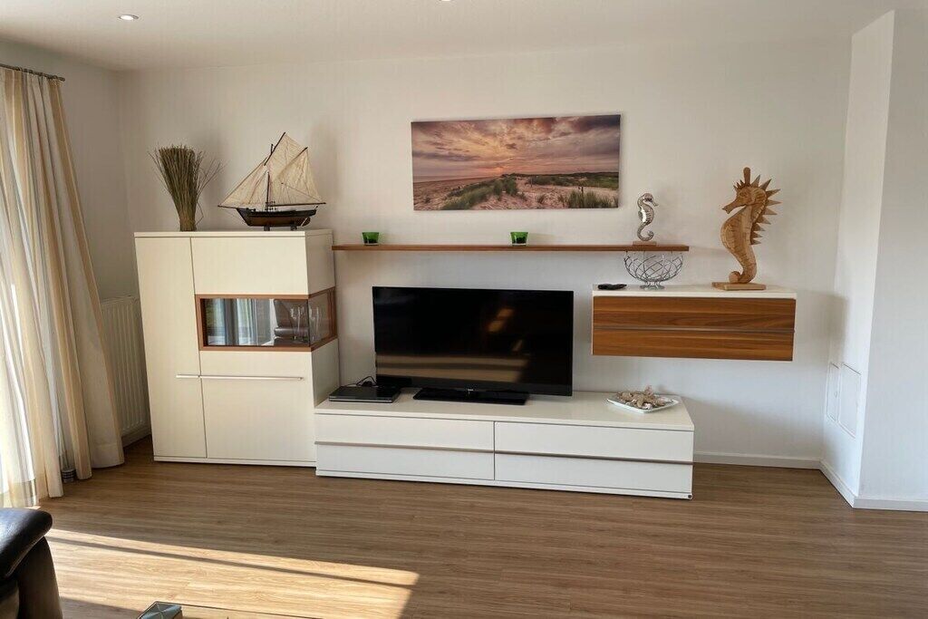 Ein modernes Wohnzimmer mit Fernseher, einem weißen Schrank, einem Holzregal und einer Meerjungfernfigur.