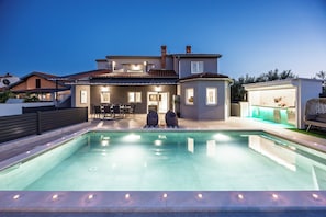 Um imóvel residencial com piscina, área de estar externa e um pátio bem iluminado.