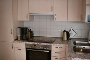Eine Küche mit eingebautem Backofen, einer Kaffeemaschine und einem Wasserkocher auf der Arbeitsplatte.