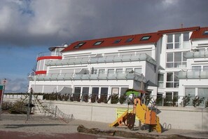 Ein mehrstöckiges Gebäude mit rotem Dach, großen Fenstern und einem Balkon im oberen Stockwerk.