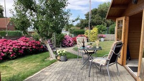 A patio with a table and chairs, surrounded by a garden with various plants and flowers. - Holiday apartment with 1 bedroom (Maasholm)