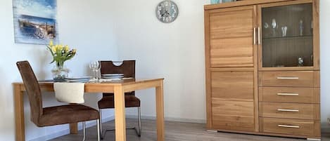 Un comedor con una mesa y sillas de madera, un reloj en la pared y un mueble con puertas de vidrio.