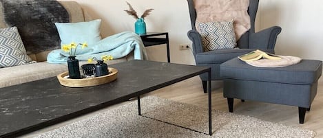 A modern living room with a sofa, armchair, coffee table, and decorative items.