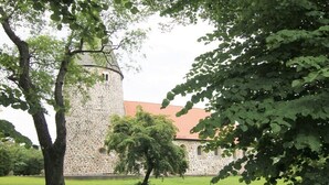 A stone building with a tower, surrounded by trees and grass. - Holiday apartment in Ratekau with barbecue (Ratekau)