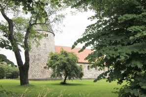 A stone building with a tower, surrounded by trees and grass. - Holiday apartment in Ratekau with barbecue (Ratekau)