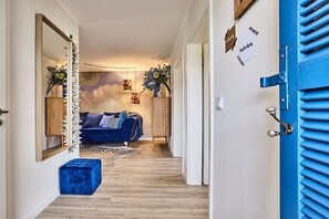 A hallway with a blue door, a blue sofa, and a mirror. - Holiday apartment in Büsum with swimming pool (Büsum)