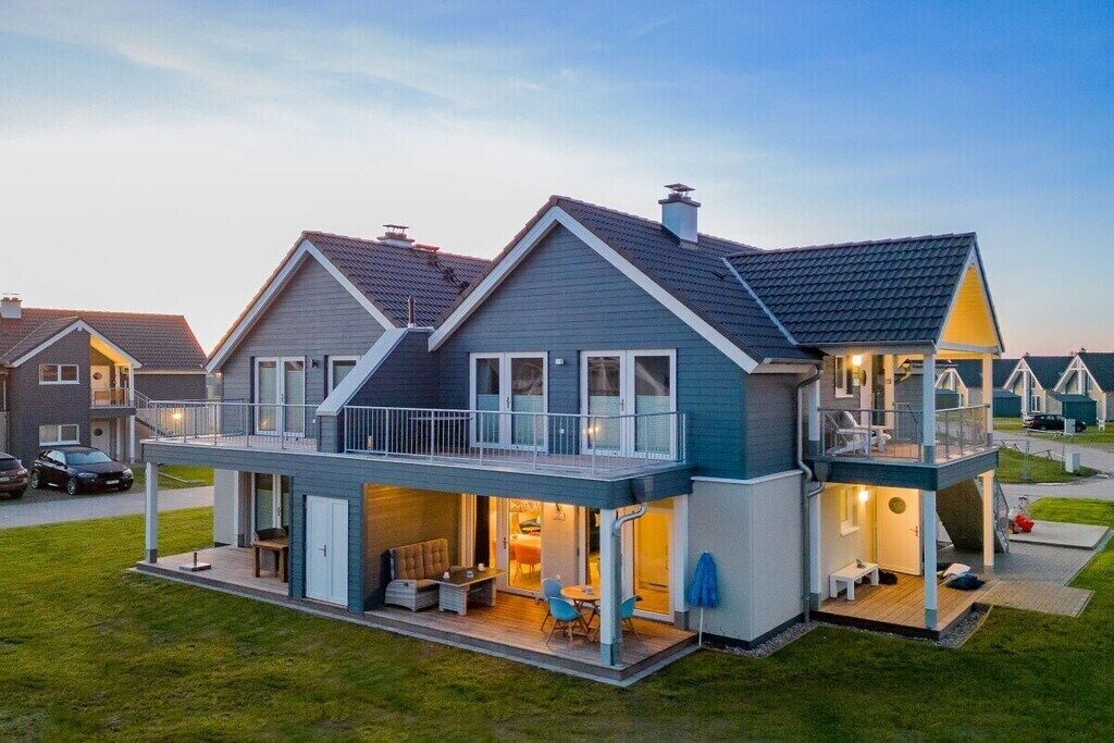 A modern two-story house with a balcony, a patio area, and a visible garage.