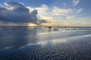 A beach with a calm sea, a few people walking, and a large cloud in the sky. - Holiday apartment in Büsum with swimming pool (Büsum)